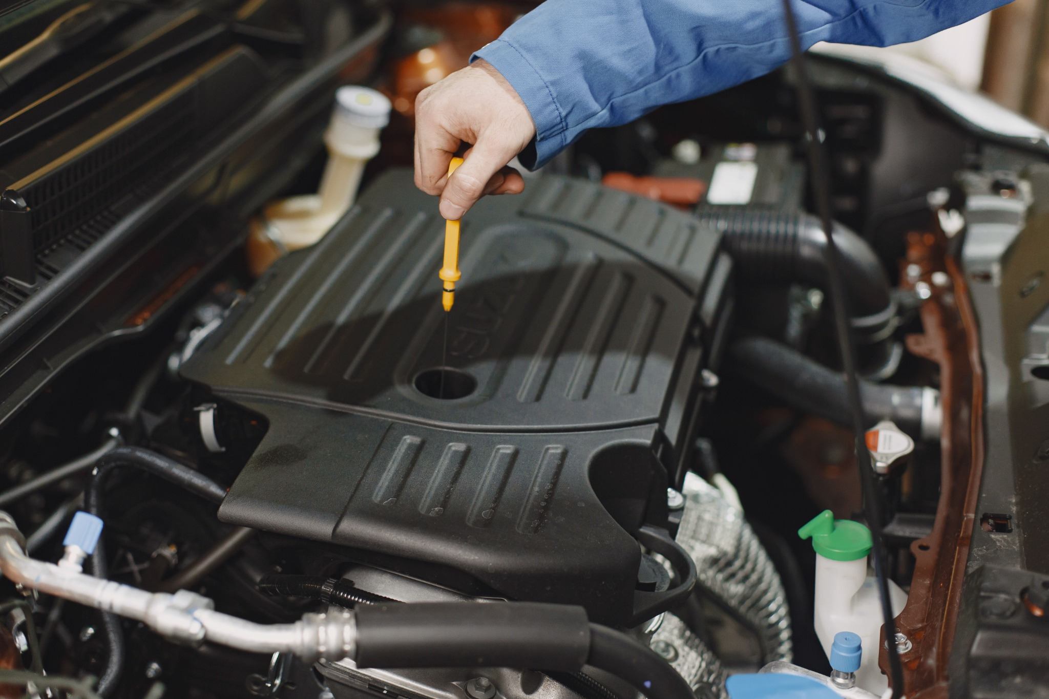 Engine oil level being checked correctly with a dipstick in a real engine bay